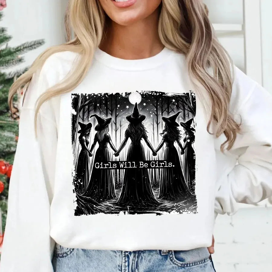 A woman wearing a white sweatshirt featuring a black and white illustration of witches silhouettes.