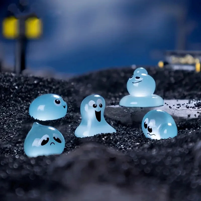 A set of eight glow-in-the-dark resin fairy water droplet figurines with various facial expressions resting on dark gravel.