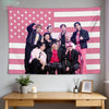 A pink American flag tapestry featuring seven Kpop idols standing in front of the flag.