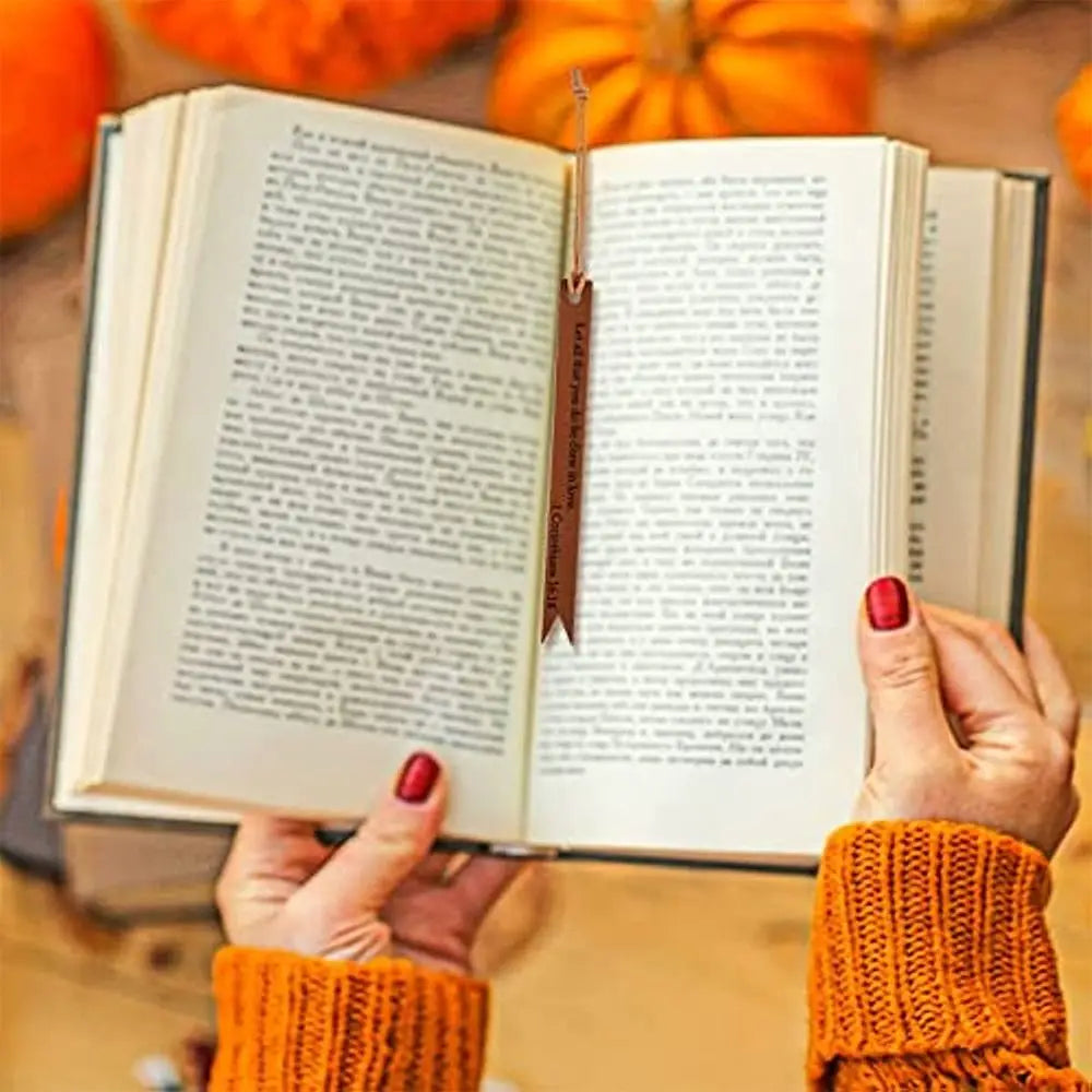 A hand holds an open leather Bible with pages and a bookmark visible.