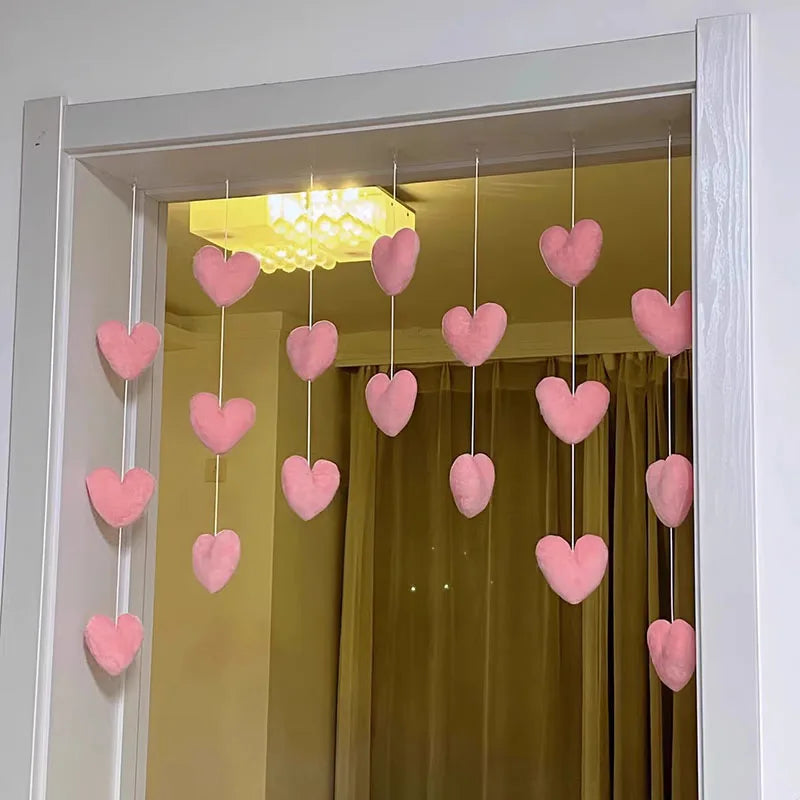 A display of heart-shaped pink string curtains hanging inside a white door frame.