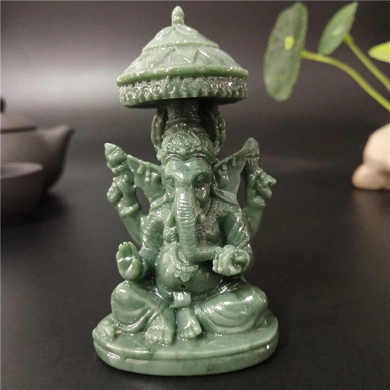 A small, green bronze statue of Ganesha Buddha with a tiered umbrella top sitting on a dark surface.