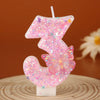 Pink glitter butterfly number three birthday candle on a wooden surface