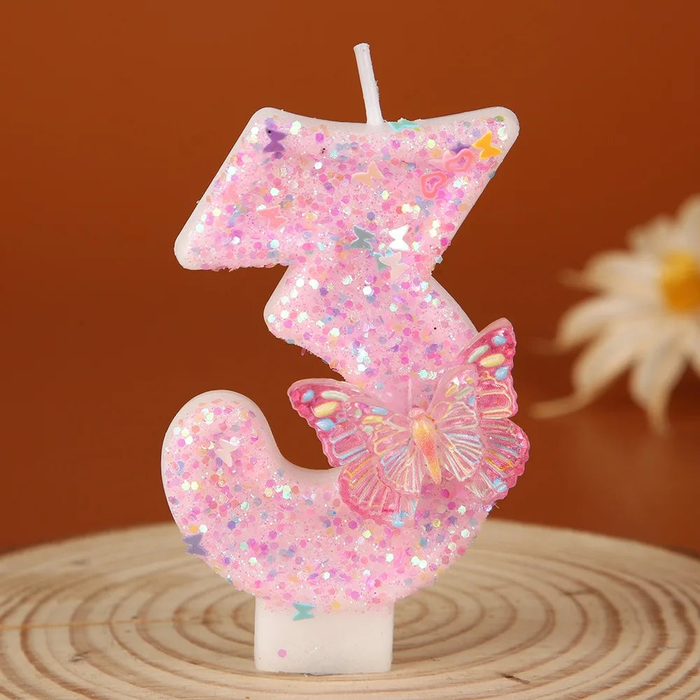 Pink glitter butterfly number three birthday candle on a wooden surface