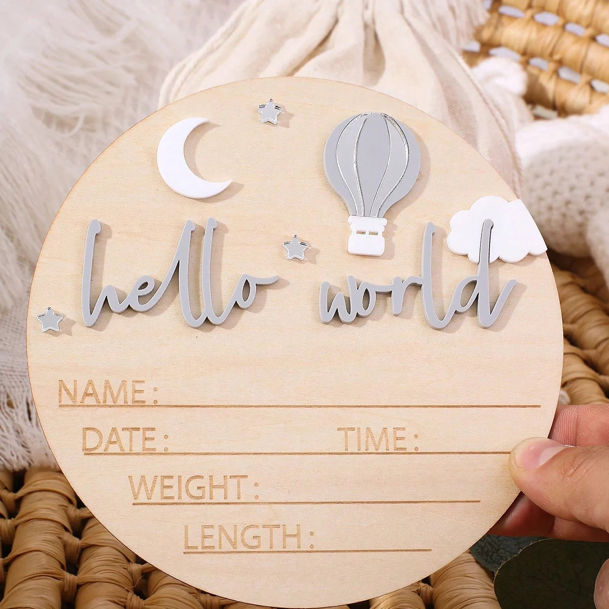 A wooden birth announcement sign featuring a crescent moon, a hot air balloon, and the text hello world.