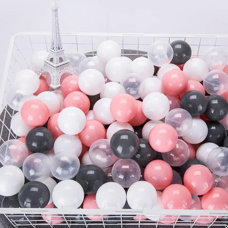 A white basket filled with a 50-pack of colorful, translucent, and opaque star-shaped balls in pink, white, and gray tones.