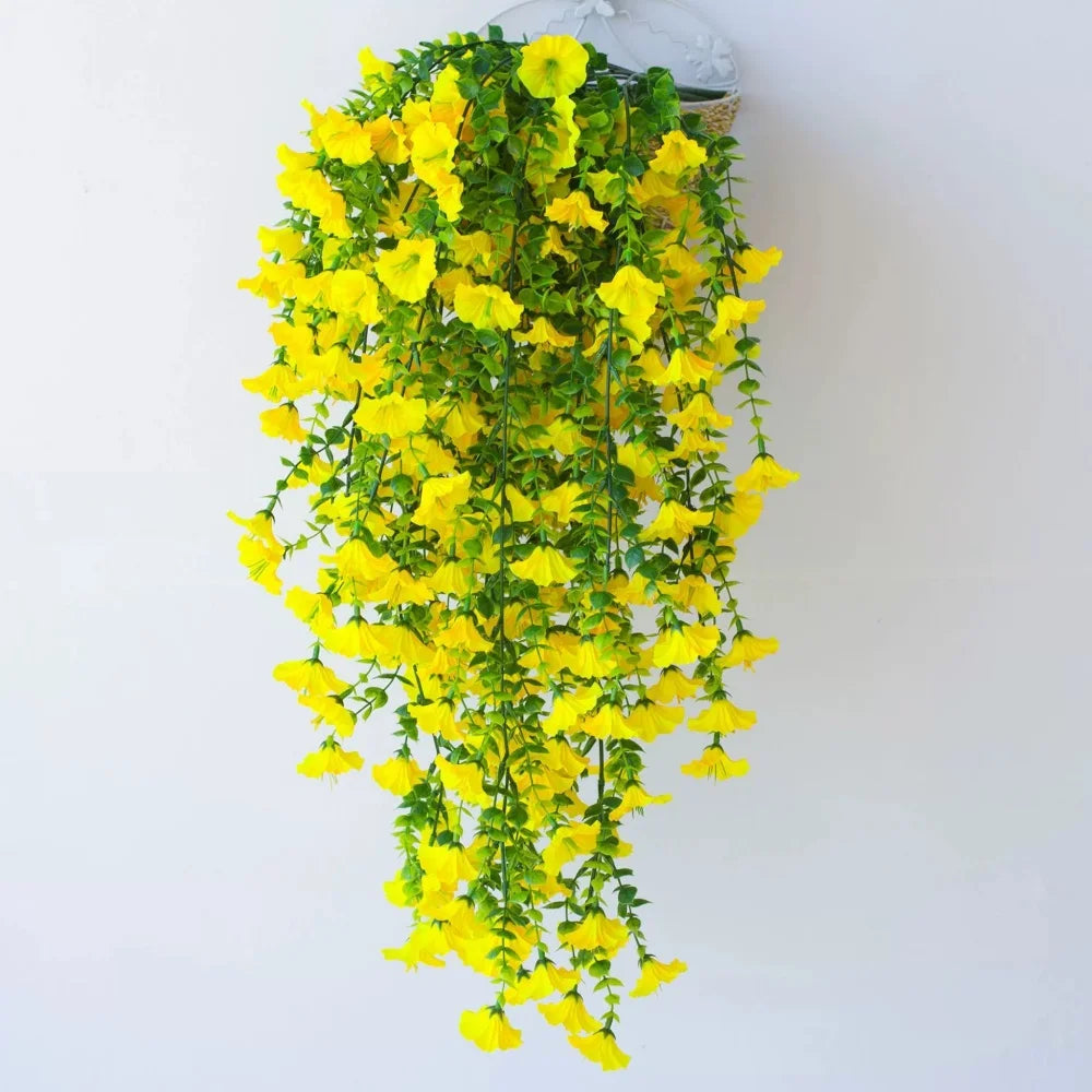 A cascading arrangement of bright yellow artificial morning glory vines hanging from a clear glass container.
