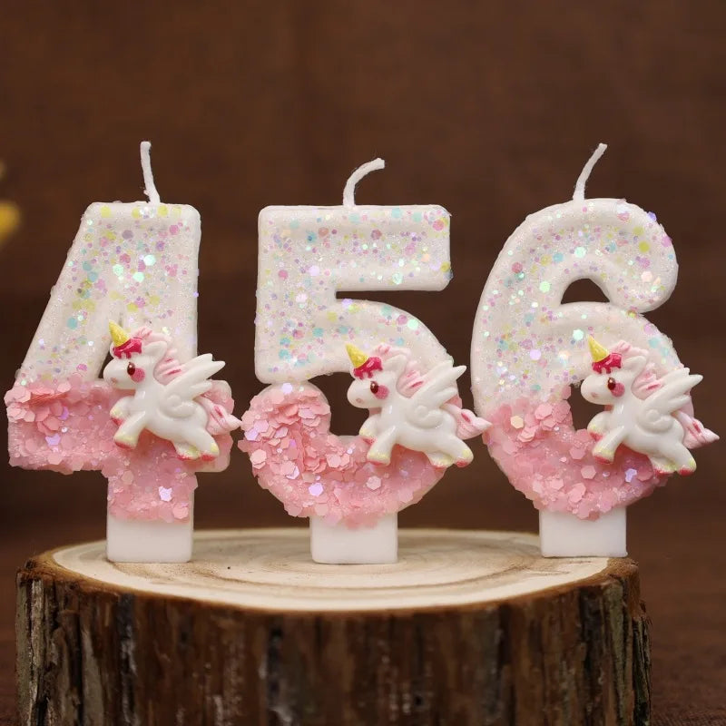 Velas de purpurina rosa y blanca con forma de los números 456, exhibidas sobre una superficie de madera.