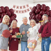 A family of four celebrating a birthday with a large arrangement of burgundy red latex balloons.