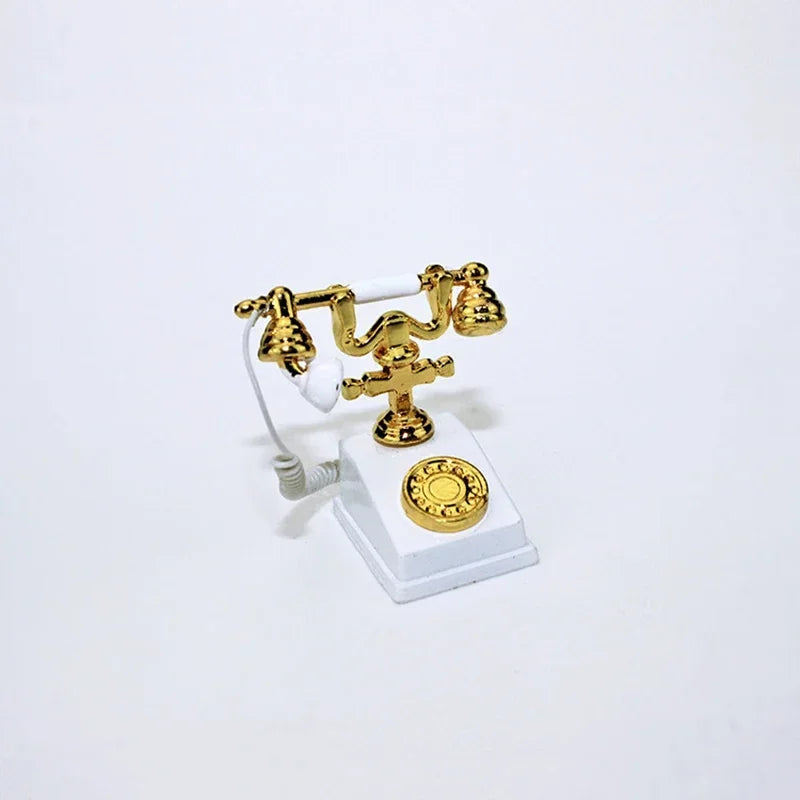 A vintage rotary desk phone miniature decor featuring brass-colored receiver and base on a white stand.