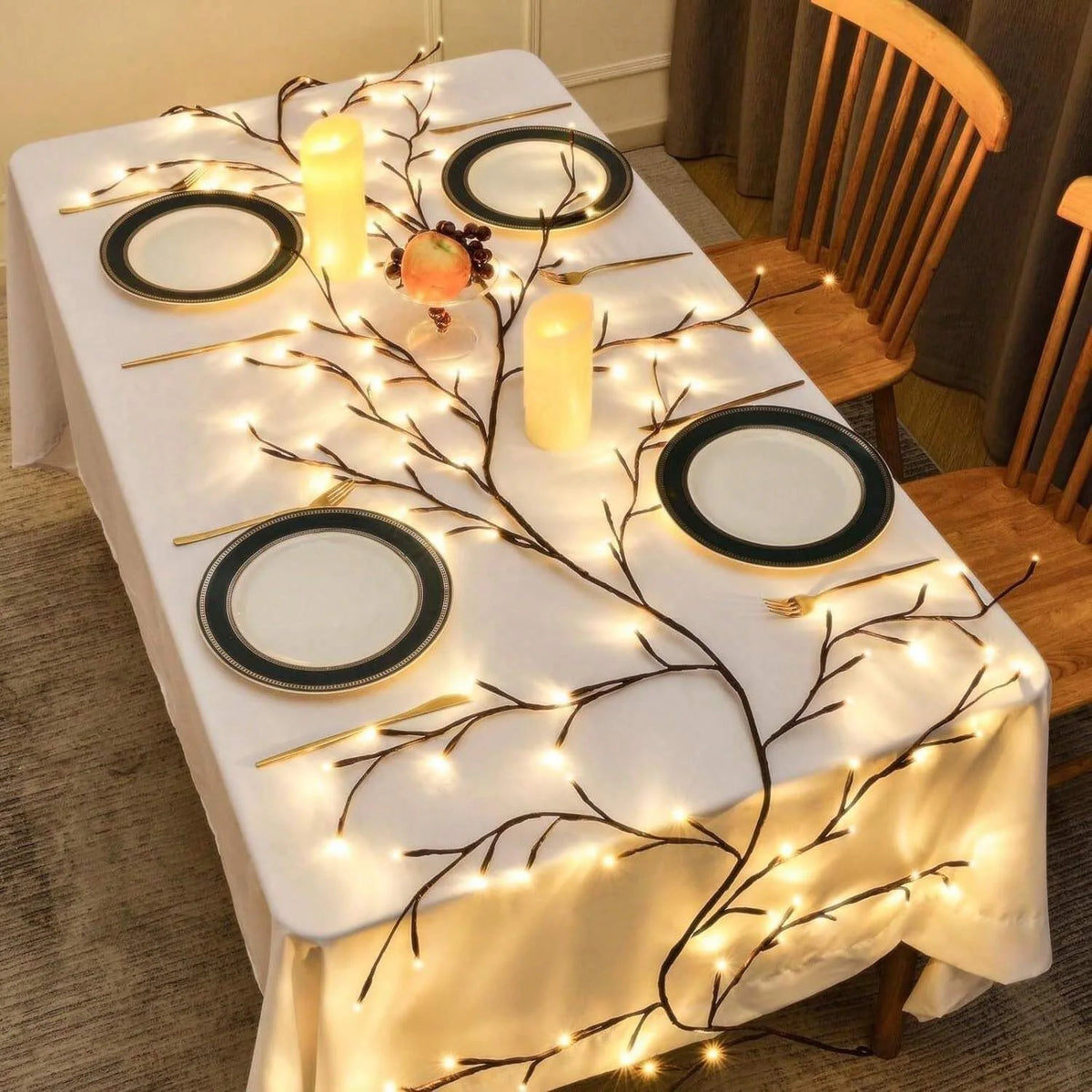 A dining table decorated with white linen and illuminated by warm white LED vine string lights forming a branch pattern.