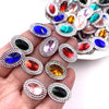 A collection of colorful gemstone flatback rhinestones in various shades of blue, red, green, and pink are displayed on a han