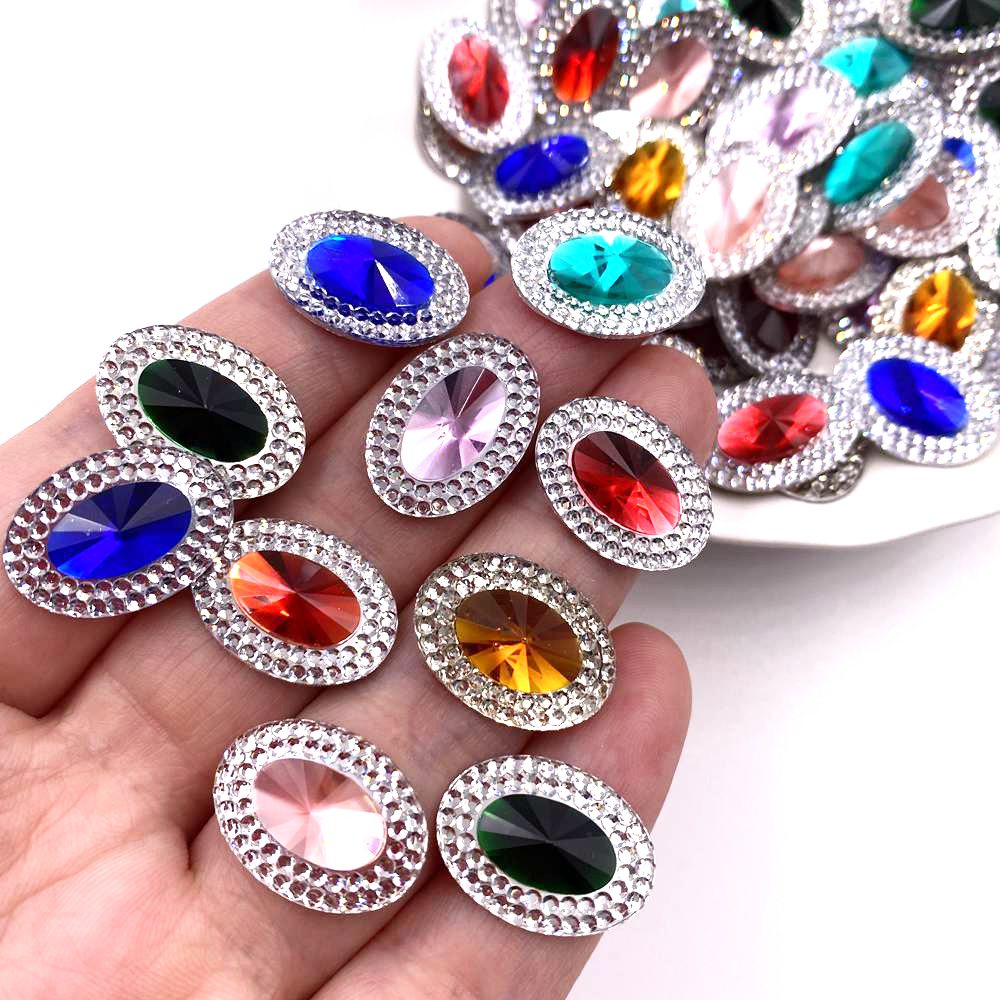 A collection of colorful gemstone flatback rhinestones in various shades of blue, red, green, and pink are displayed on a han