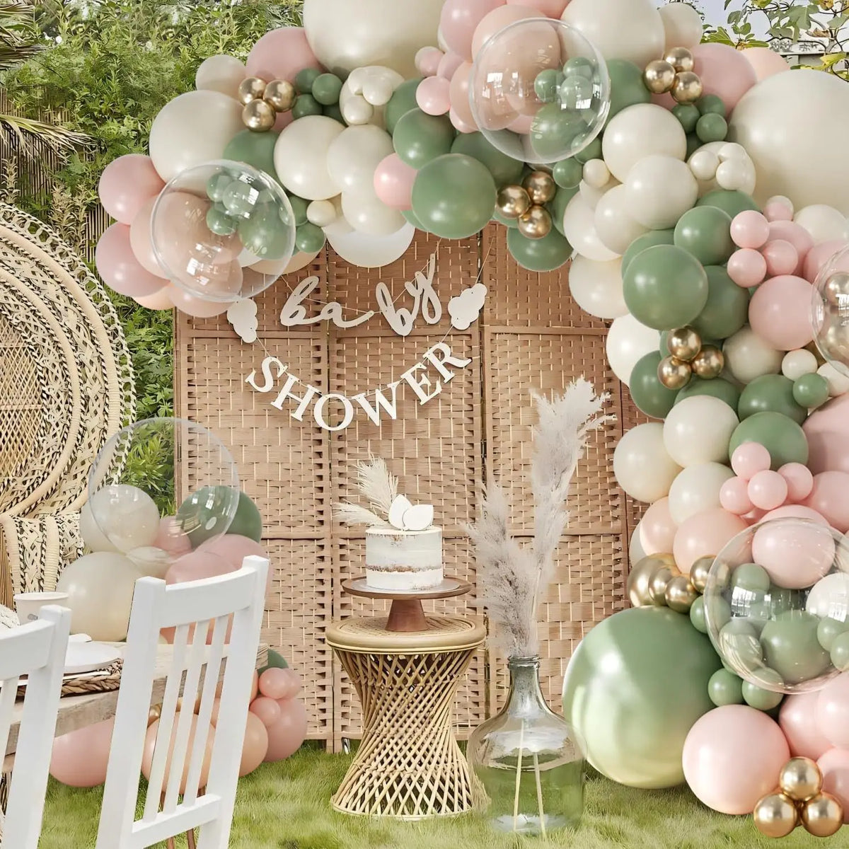 A pink latex balloon arch kit setup featuring white, green, and blush balloons decorating a wooden backdrop for a baby shower