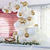A large balloon arch featuring white and gold balloons decorated with greenery for an event backdrop.