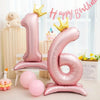 Pink foil number balloons spelling '16' with gold crowns and pink confetti