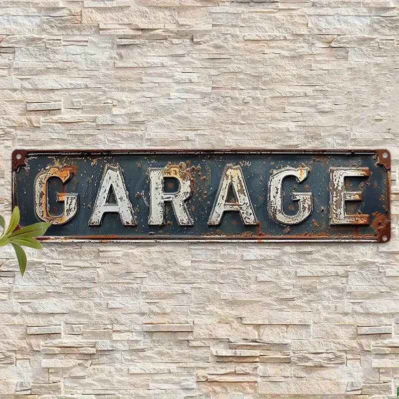 A weathered, dark metal sign with the word GARAGE mounted on a light-colored stone wall.