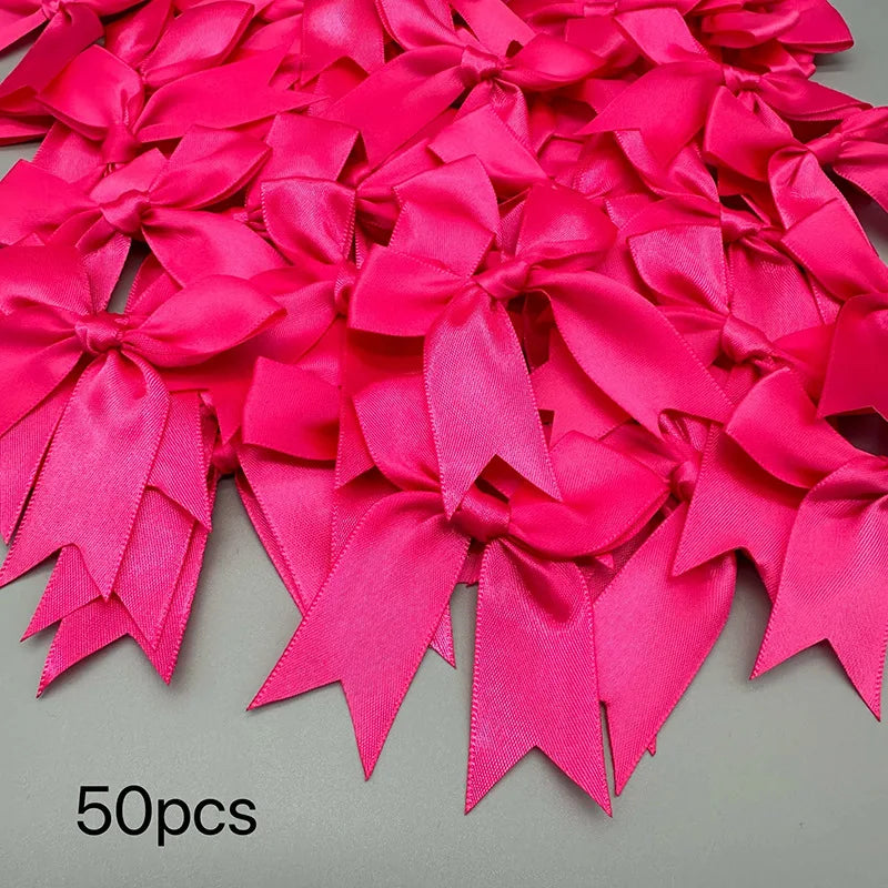 A pile of bright pink satin ribbon bows for gift wrapping and decor, showing various folds and sizes.