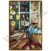 A vintage metal sign featuring a painting of a bottle, flowers, and a bicycle.
