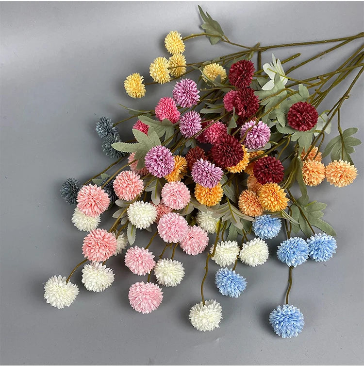 Una ráfaga de flores artificiales de crisantemo y diente de león en tonos rosa, amarillo, rojo y azul.