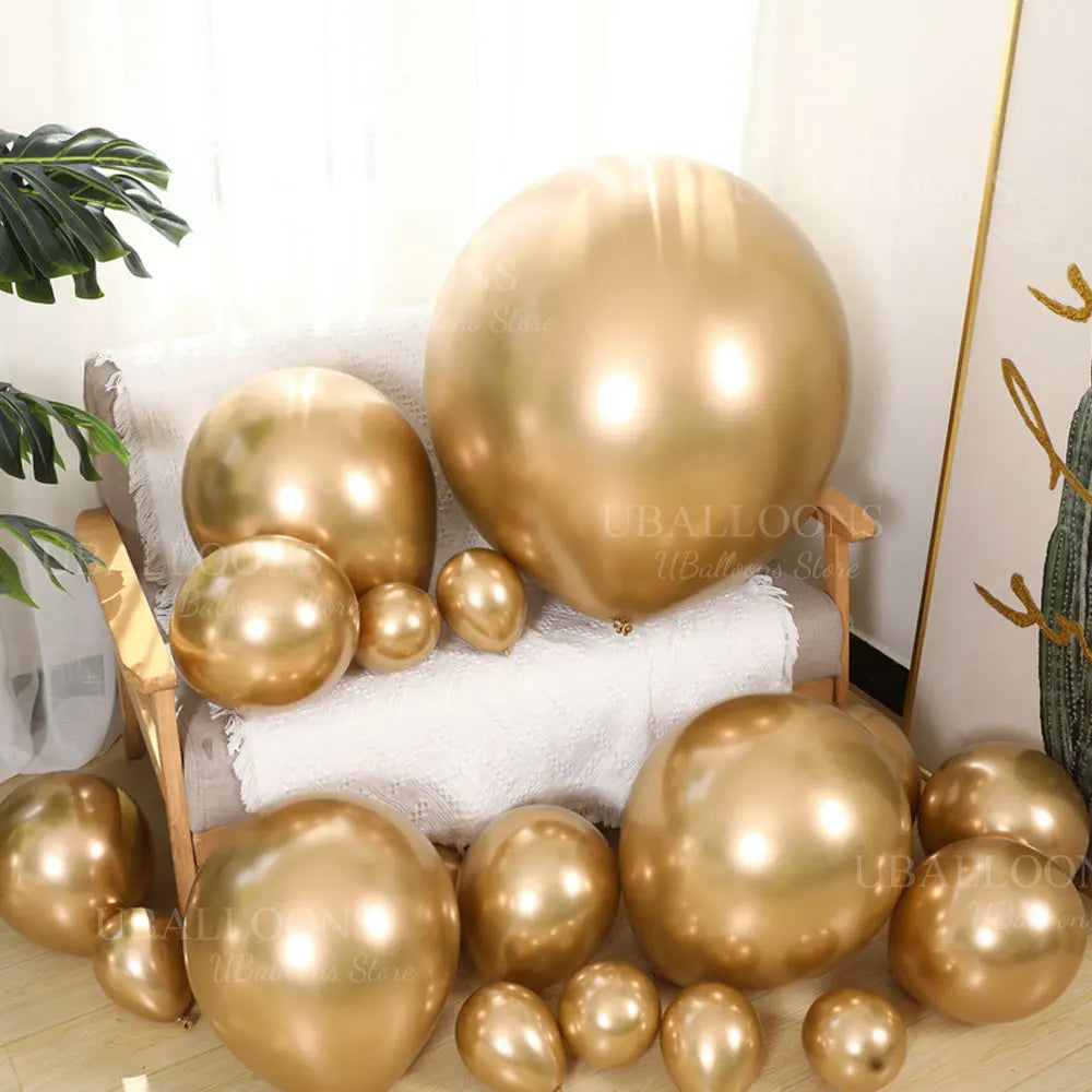 A collection of metallic gold balloons arranged on a white towel and wooden surface.