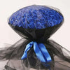 A dark blue silk rose bouquet wrapped in sheer black fabric with a bright blue ribbon.