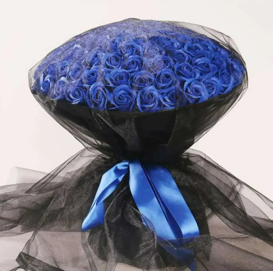 A dark blue silk rose bouquet wrapped in sheer black fabric with a bright blue ribbon.