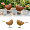 Two rustic metal bird sculptures in brown and gold colors standing on a stone surface.
