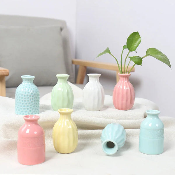 A collection of handcrafted ceramic mini vases in various pastel shades, including pink, mint green, yellow, and blue, displa