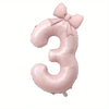 Large pink foil number balloon shaped like the number 3 with a bow