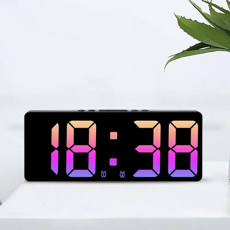 A black digital alarm clock displaying 18:38 in vibrant pink and purple light on a white surface.