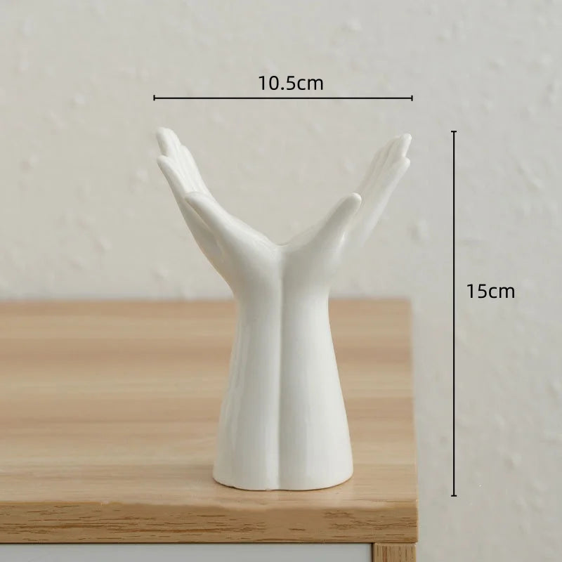 A white ceramic hand sculpture shaped like an open hand, used as a vase for home décor.