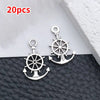 A pair of silver vintage ship anchor charms for jewelry making displayed on a dark surface.