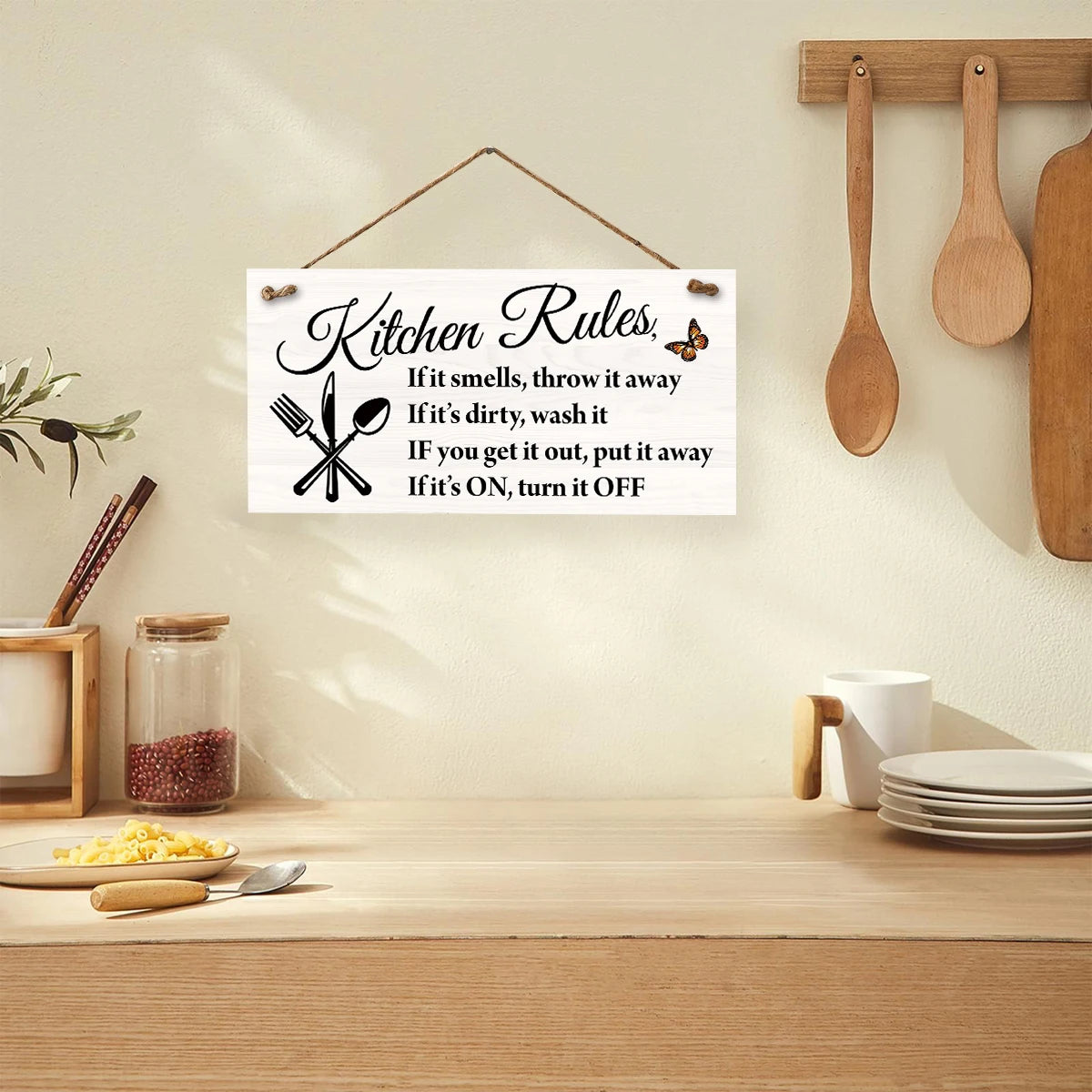 A wooden hanging sign with black text listing kitchen rules such as throwing away smells and turning off appliances.