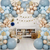 A floral balloon wreath display featuring blue, sand, white, and gold latex balloons arranged in an archway.