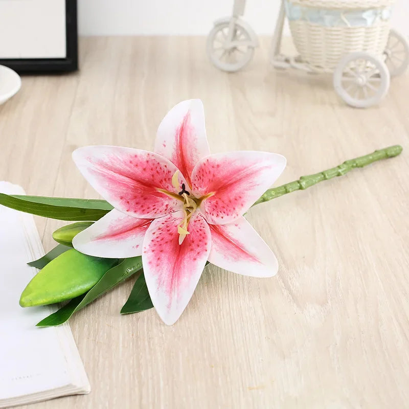 A realistic silk lily flower with three pink and white blooms on a green stem.