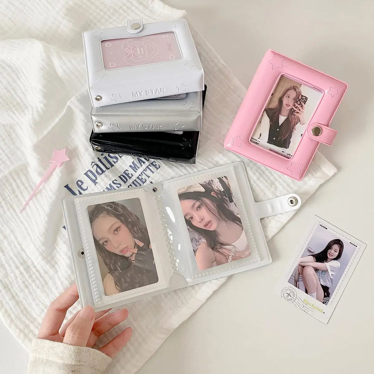 A pink compact photo card holder album with two pages is displayed on a white textured cloth.