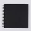 A black spiral-bound notebook or scrapbook for DIY memory keeping.