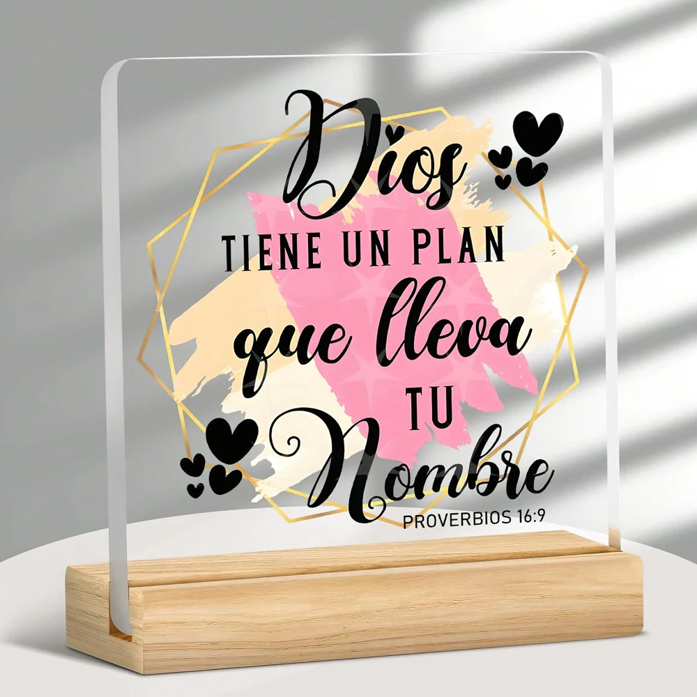 A clear acrylic sign featuring the Spanish Bible verse Proverbs 16:9 in elegant script on a light background.