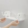 Hands are installing a white elephant storage rack for wall organization onto a bathroom tile.