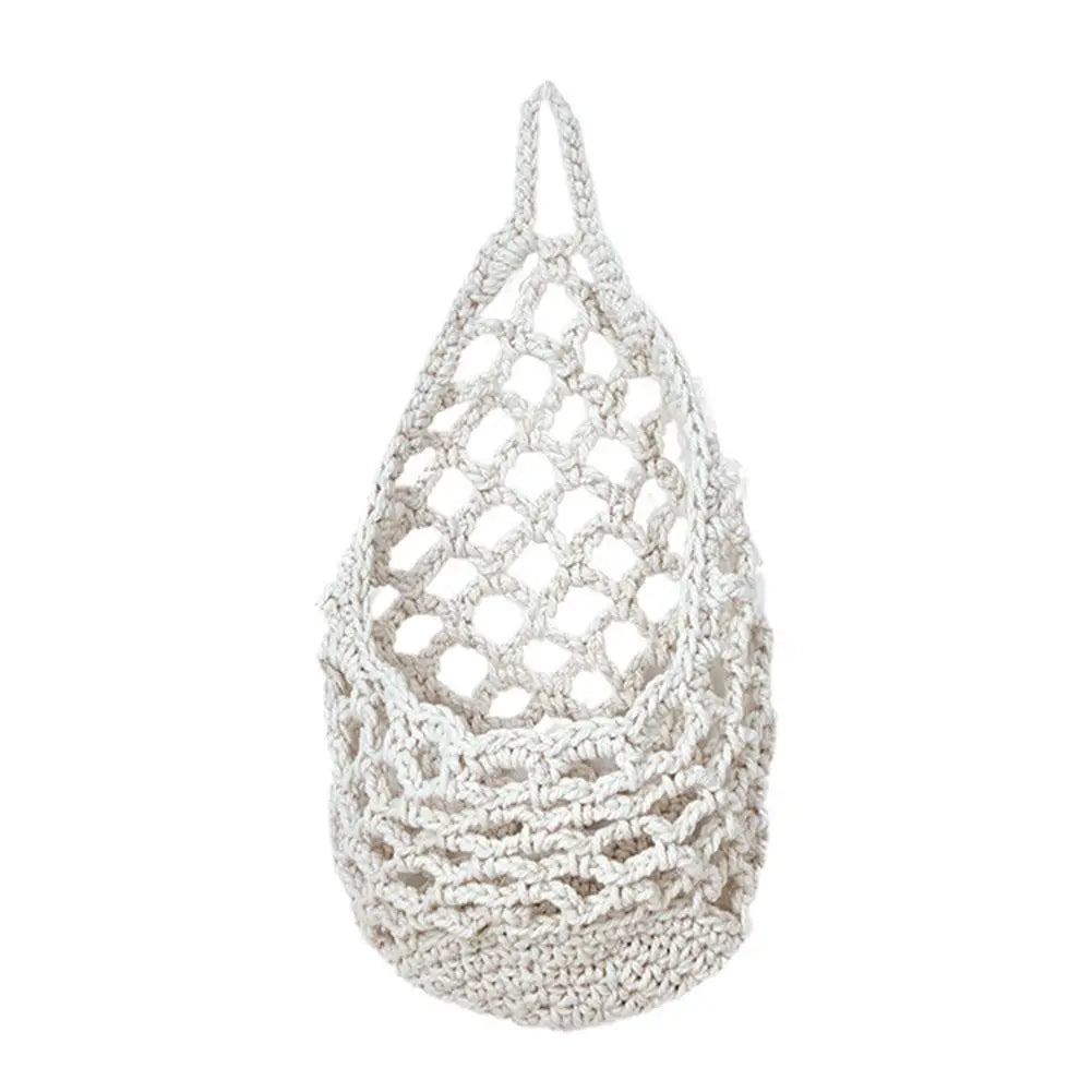 A white boho macrame hanging storage basket with a netted, organic texture.
