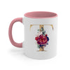 A pink ceramic coffee mug featuring a gold letter T design with floral accents.