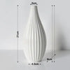 A tall, white ceramic flower vase with vertical ribbed texture.