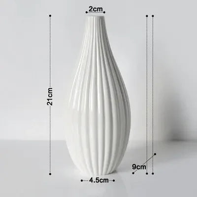 A tall, white ceramic flower vase with vertical ribbed texture.