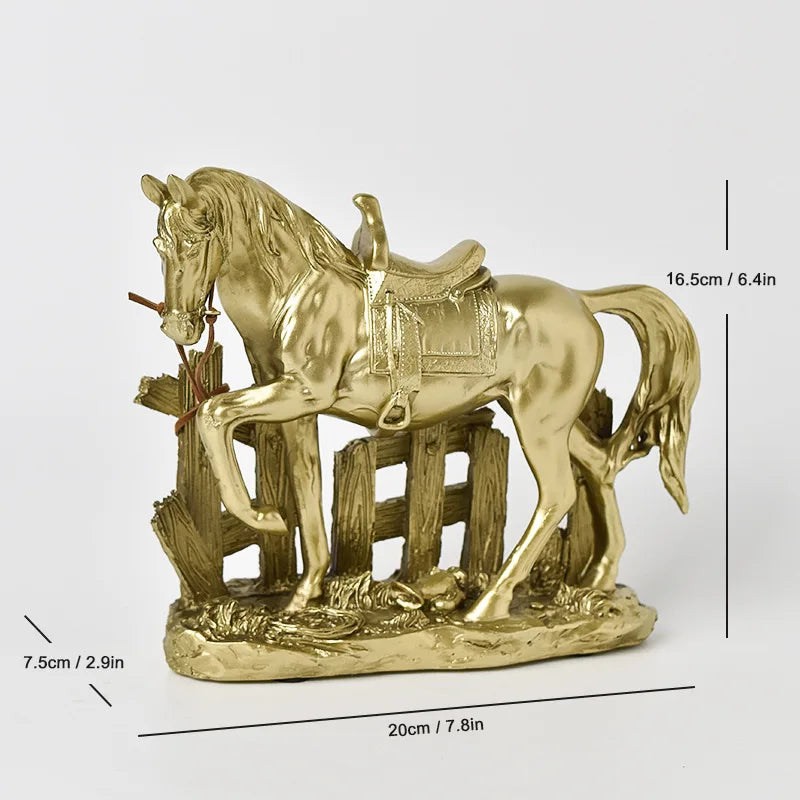 A gold-colored sculpture of a horse standing next to a wooden fence and straw, depicting a rustic western scene.