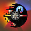 A vinyl record shaped wall lamp featuring silhouettes of figures and a clock face against a colorful background.