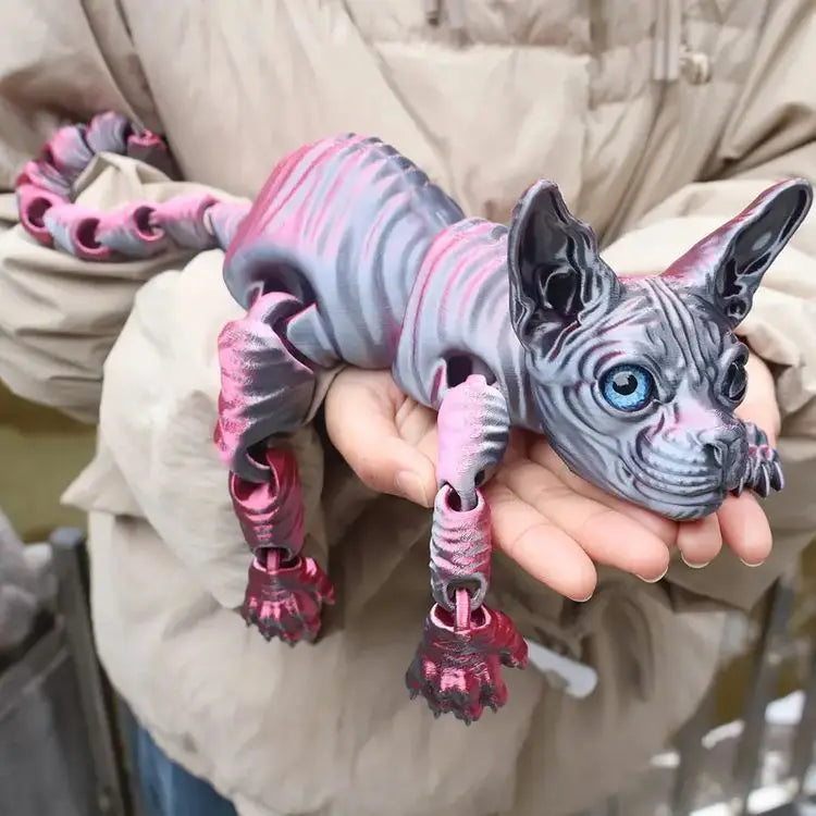 A hand holds a realistic Sphynx cat fidget toy with pink and gray striped fur.