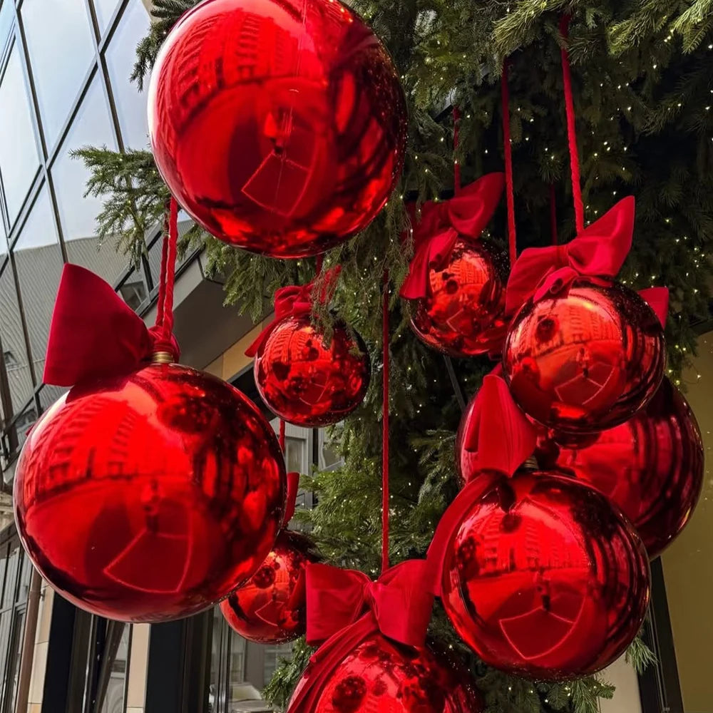 A cluster of glossy red round foil balloons tied to a green Christmas tree branch.