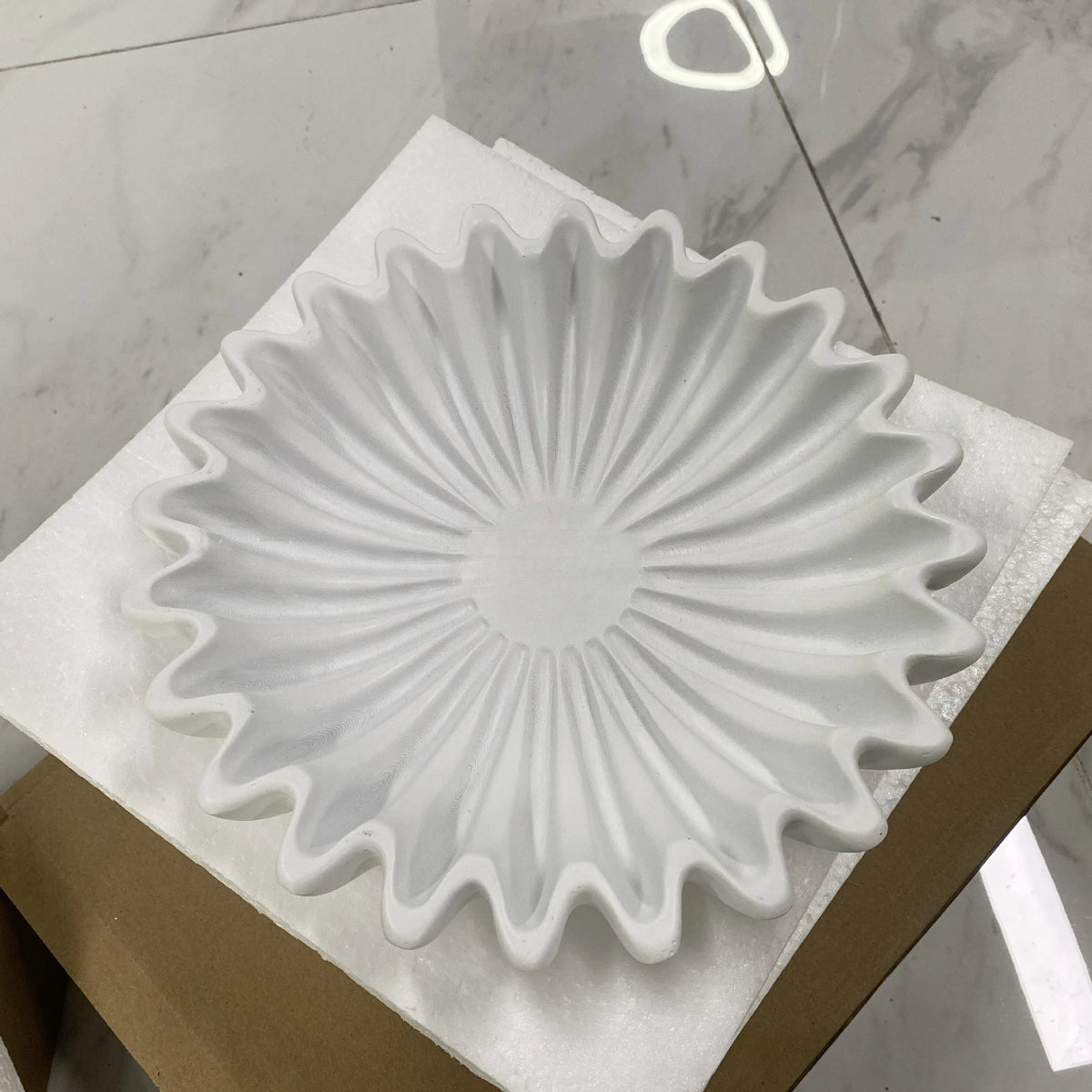 A white lotus leaf resin decorative bowl is displayed on a brown cardboard box.
