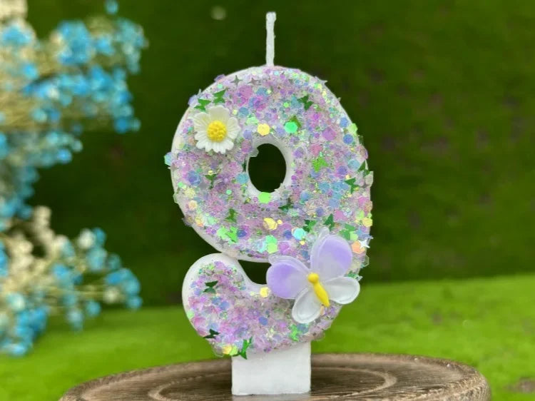 A white number cake candle shaped like the number 8 decorated with purple and yellow flowers and a purple butterfly